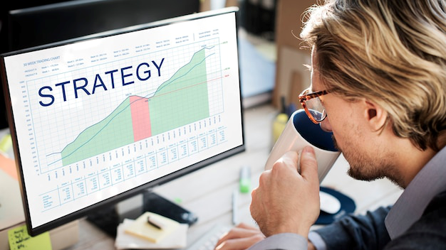 a man drinking a coffee while looking at a computer screen